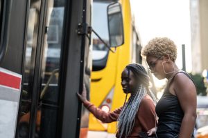 Duas mulheres entrando num ônibus e vendo com a mobilidade urbana impacta na vida delas